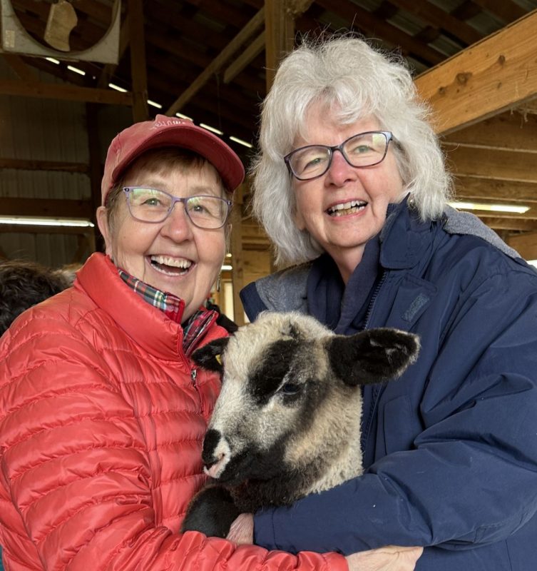 Two women holding a lamb