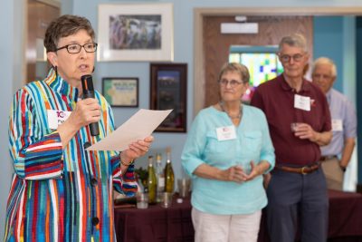 A woman speaks into a microphone as others look on. 